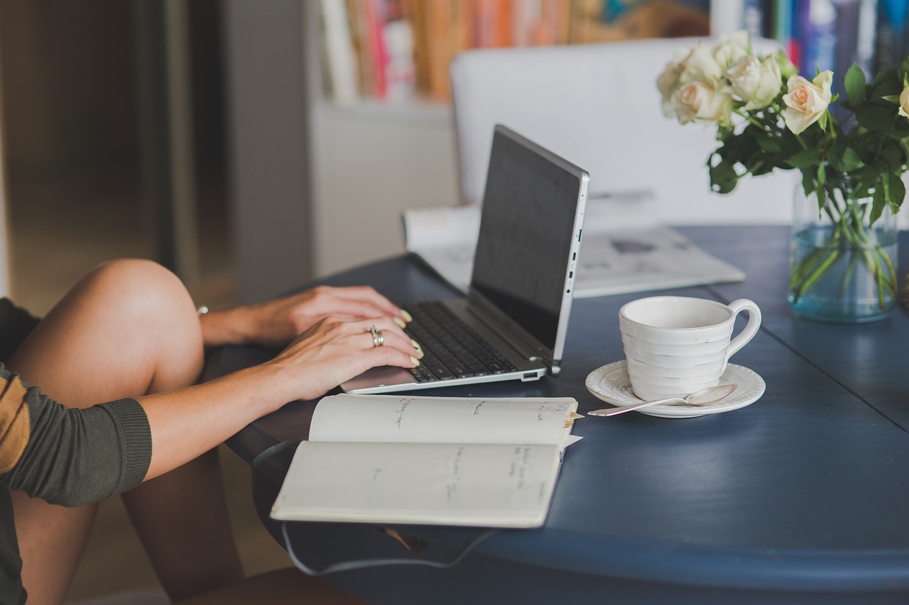 A laptop open on a wooden desk beside a notebook and a cup of coffee, the kind of desk where an owner opens the Search Console report for the first time